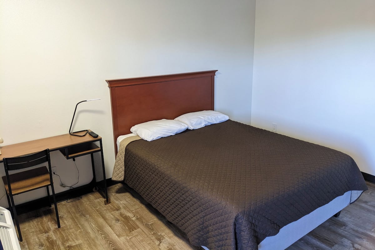 A bedroom with a bed, a desk, and a chair.