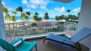 A balcony with a view of a beach, palm trees, and a clear sky. - Sleep with the sound of waves! (Carolina)