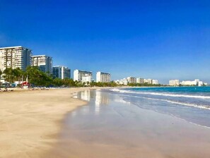 Una playa con una orilla arenosa y una fila de edificios altos al fondo.