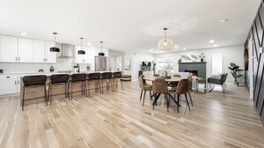 A modern kitchen with white cabinets, a central island with bar stools, and a dining area with a round table and chairs.