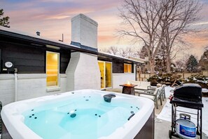 Una casa moderna con hidromasaje, mobiliario exterior y un tanque de propano.