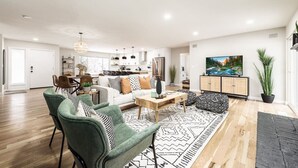 A spacious living room with a sofa, chairs, a coffee table, and a TV.