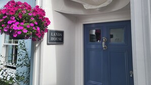 A blue door with a sign reading "LANDS HOUSE" and a hanging flower basket. - Lands House (Bideford)