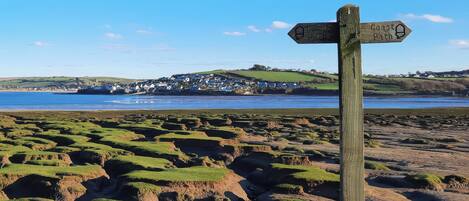 A wooden signpost with directional arrows pointing towards 'Coast Path' and 'Colne Path'.