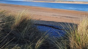 A beach with clear skies and distant hills. - Mulberry Tree (Bideford)