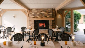 Zona pranzo all'aperto con pareti in mattoni, travi di legno e tavoli con sedie.