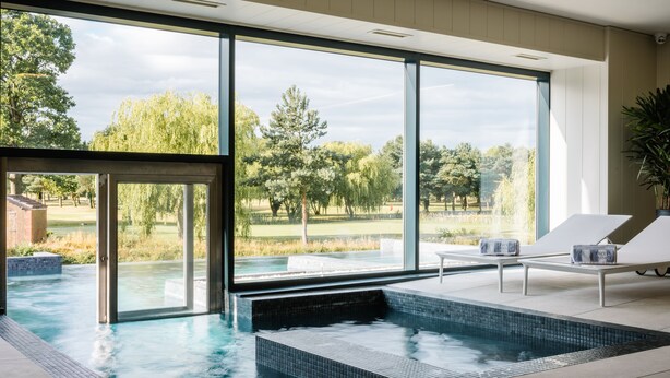 Una piscina interna moderna con ampie vetrate che si affacciano su un parco.