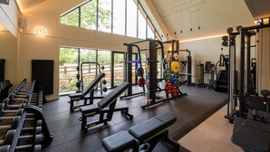 Una palestra con attrezzature per sollevamento pesi, panche e ampie finestre.