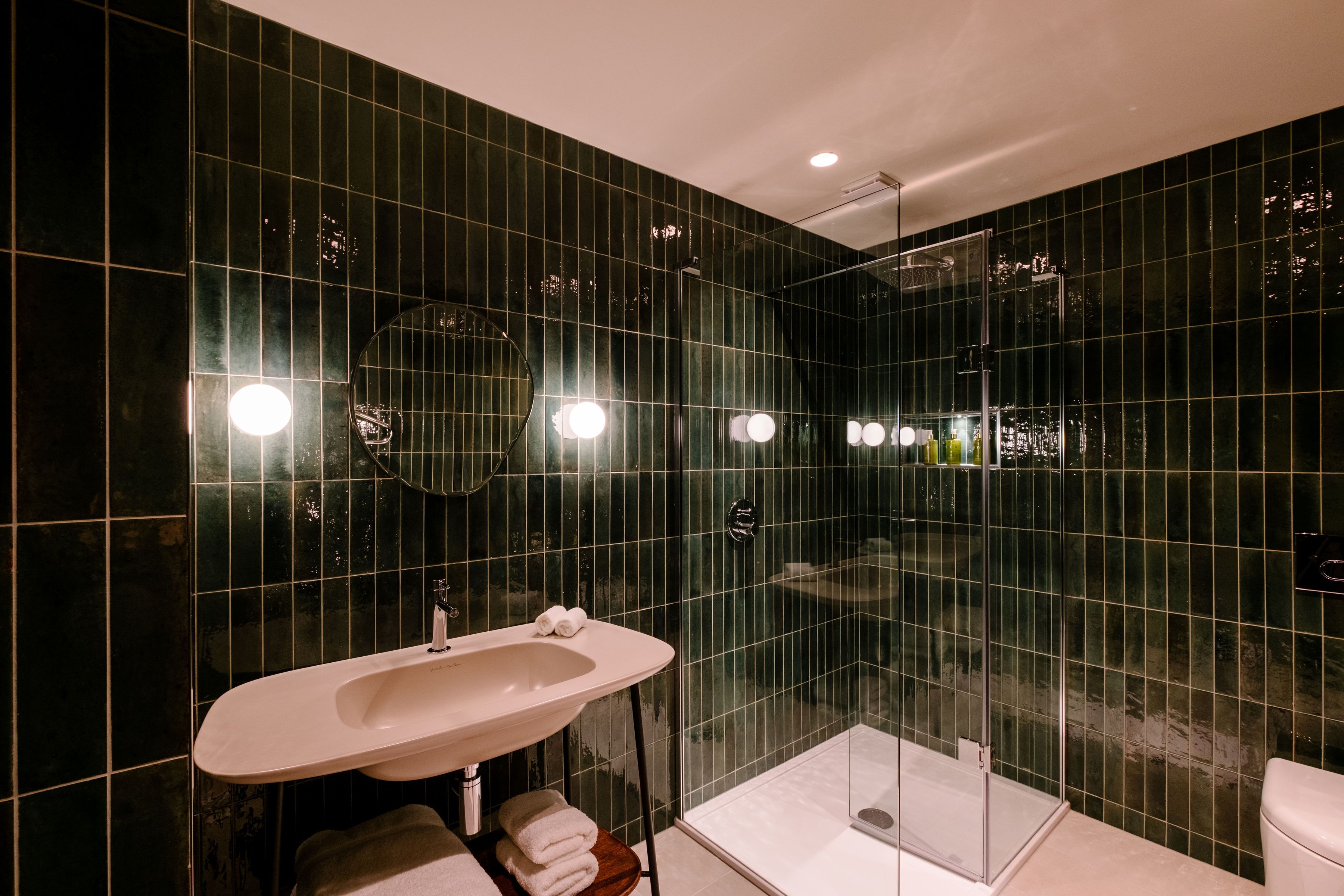 Un baño moderno con un lavamanos grande, espejo y ducha con mampara de vidrio.