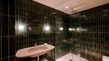 Un baño moderno con un lavamanos grande, espejo y ducha con mampara de vidrio.