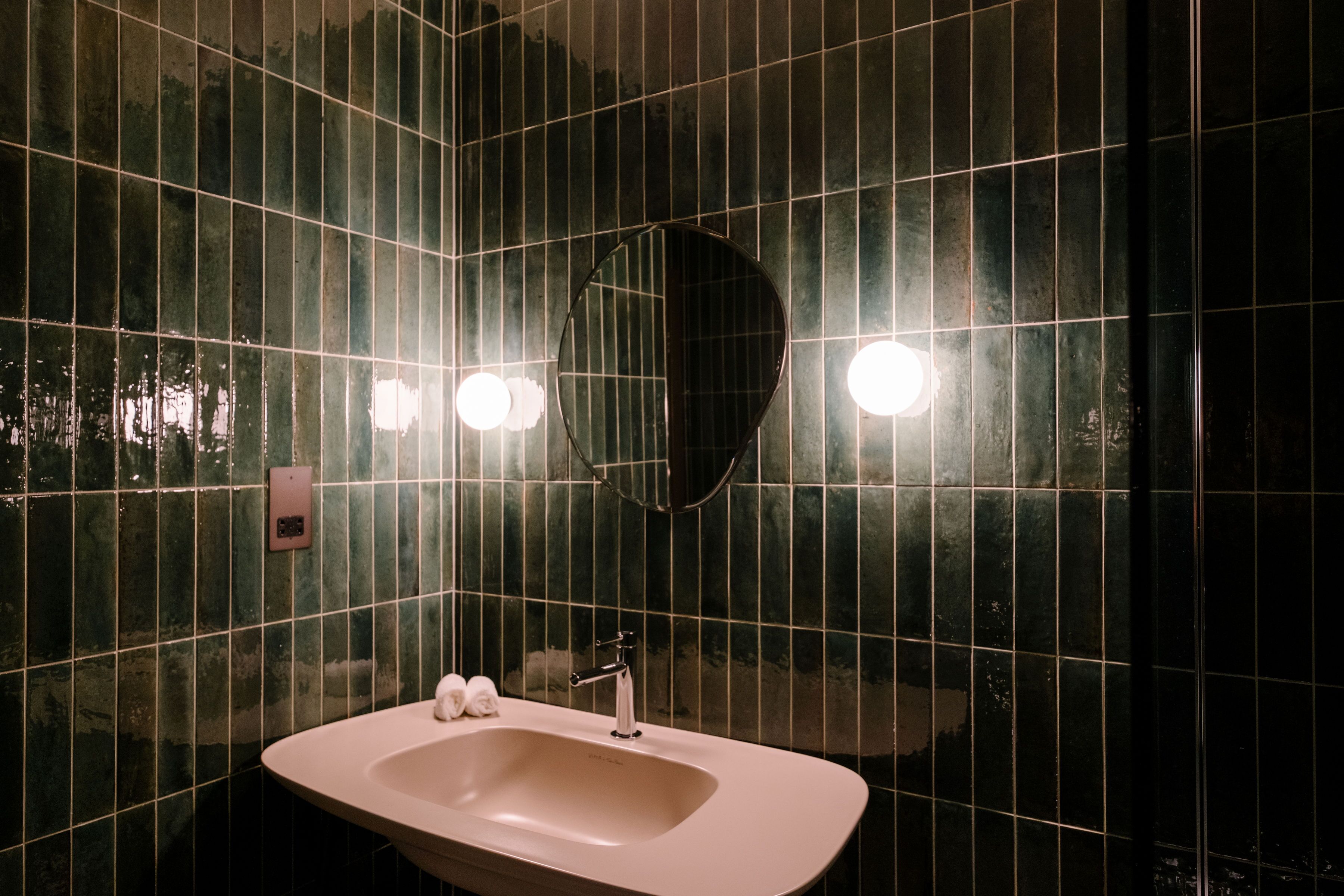 A bathroom with a sink, mirror, and tiled walls.