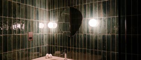Un baño con lavabo, espejo y paredes de azulejos.