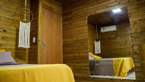 A wooden cabin room with a bed, a door, and a mirror. - Cabanas Aconchego dos Canyons (Praia Grande)