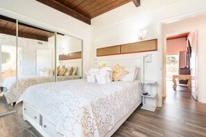 A bedroom with a large bed, bedside tables, a mirror, and a wooden ceiling.