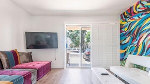Una sala de estar moderna con un sofá, un banco y un televisor montado en la pared.