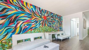 Una sala de estar moderna con un sofá blanco, una mesa de centro y un cuadro abstracto y colorido en la pared.