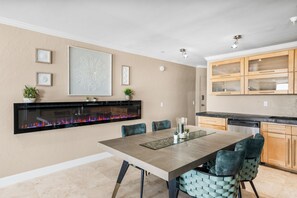 A modern kitchen with a dining area, featuring a built-in fireplace, wooden cabinets, and a large dining table.