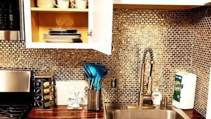Una cocina con un lavamanos de acero inoxidable, un respaldo de ladrillo y una encimera de madera.