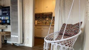 A cozy room with a hanging chair, a television, and a patterned wall. - Tuluminati:BohoChic Condo Steps from Ocean and Bay (San Diego)