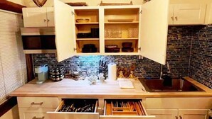 A kitchen with open cabinets, a sink, and a countertop with various kitchen items. - Luxe Thai-Inspired Condo Steps to Beach w/ Parking (San Diego)