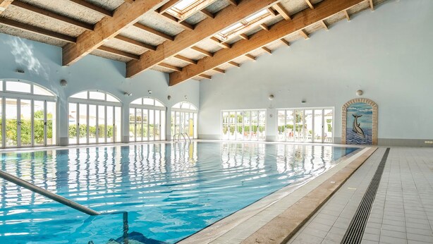 An indoor swimming pool with wooden beams, large arched windows, and a dolphin mural. - Lovely 2 Bedroom Apt, Oasis Parque, Alvor (Portimão)