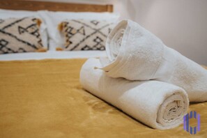 A neatly made bed with white towels and a patterned pillow.