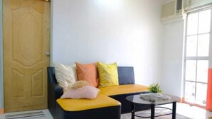A living room with a sofa, a coffee table, and a door. - Tranquil Retreat: Inviting 2BR Condo in Zamboanga (Zamboanga)
