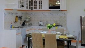 A modern kitchen with white cabinets, a marble backsplash, and a dining area with a table and chairs. - Tranquil Retreat: Inviting 2BR Condo in Zamboanga (Zamboanga)