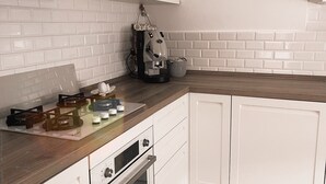 Una cocina moderna con armarios blancos, horno empotrado, cafetera y encimera de madera.