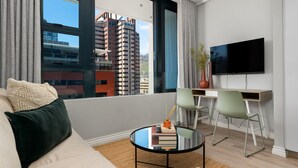 A modern living room with a sofa, a coffee table, and a TV mounted on the wall. - Modern Studio On Bree Street (Cape Town)
