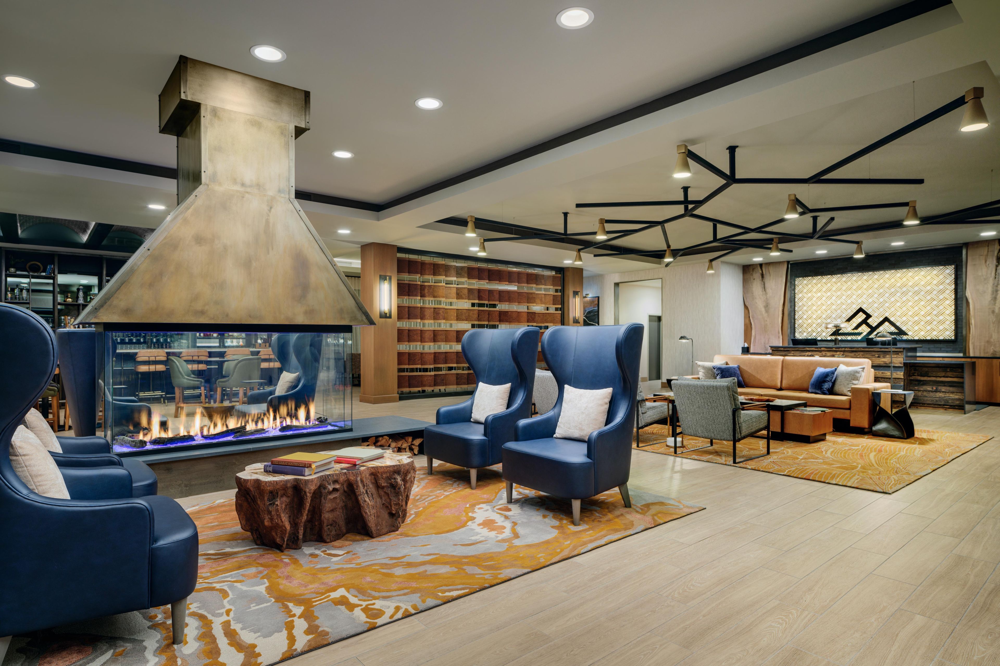 A modern living room with a fireplace, seating, bookshelves, and a unique ceiling design.