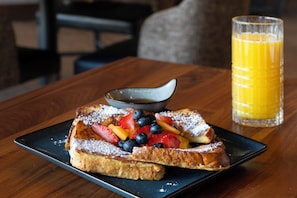 A breakfast plate with French toast, blueberries, strawberries, and a glass of orange juice on a wooden table. - The Hoffmann Hotel Basalt Aspen, Tapestry Collection By Hilton (Basalt)