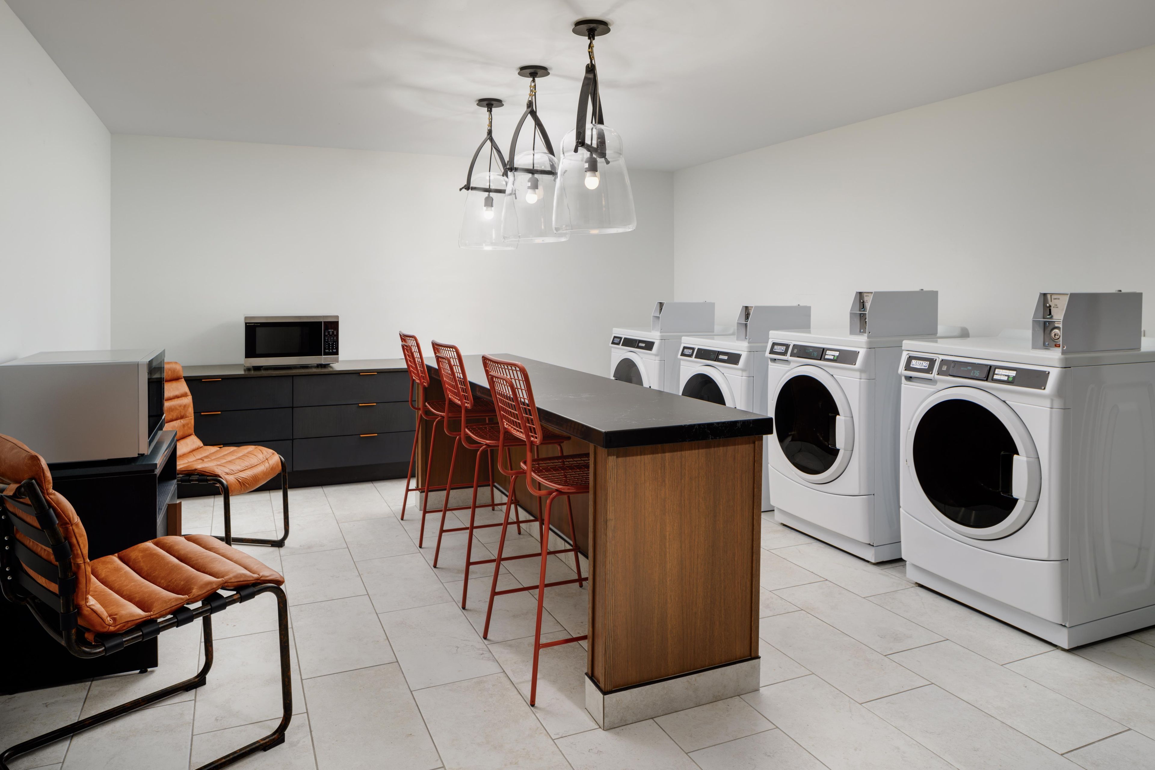 A modern kitchen with a central island, a dining area with chairs, and a washing machine.