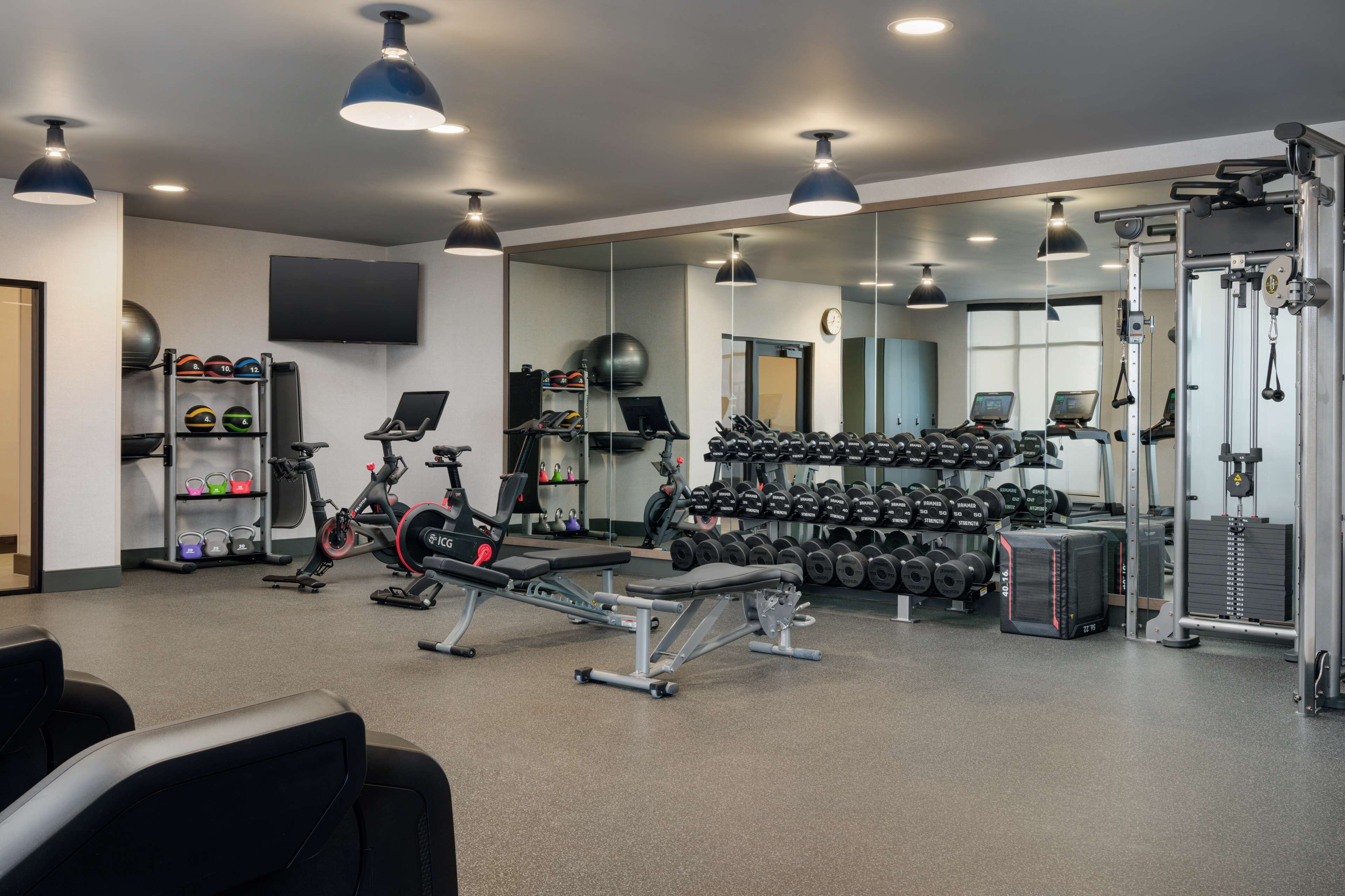A gym with exercise equipment, dumbbells, and a mirrored wall.