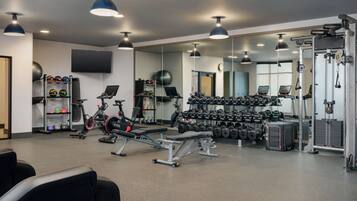 A gym with exercise equipment, dumbbells, and a mirrored wall.