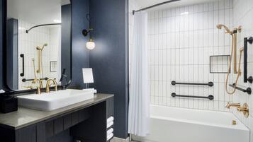 Un baño moderno con un lavamanos grande, espejo y zona de ducha.