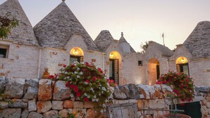 A stone building with conical roofs and arched windows, featuring stone walls and flower boxes.