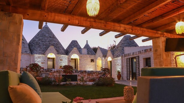 A stone building with a wooden roof and a garden area with outdoor seating.