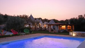 A swimming pool with a stone wall and colorful chairs.