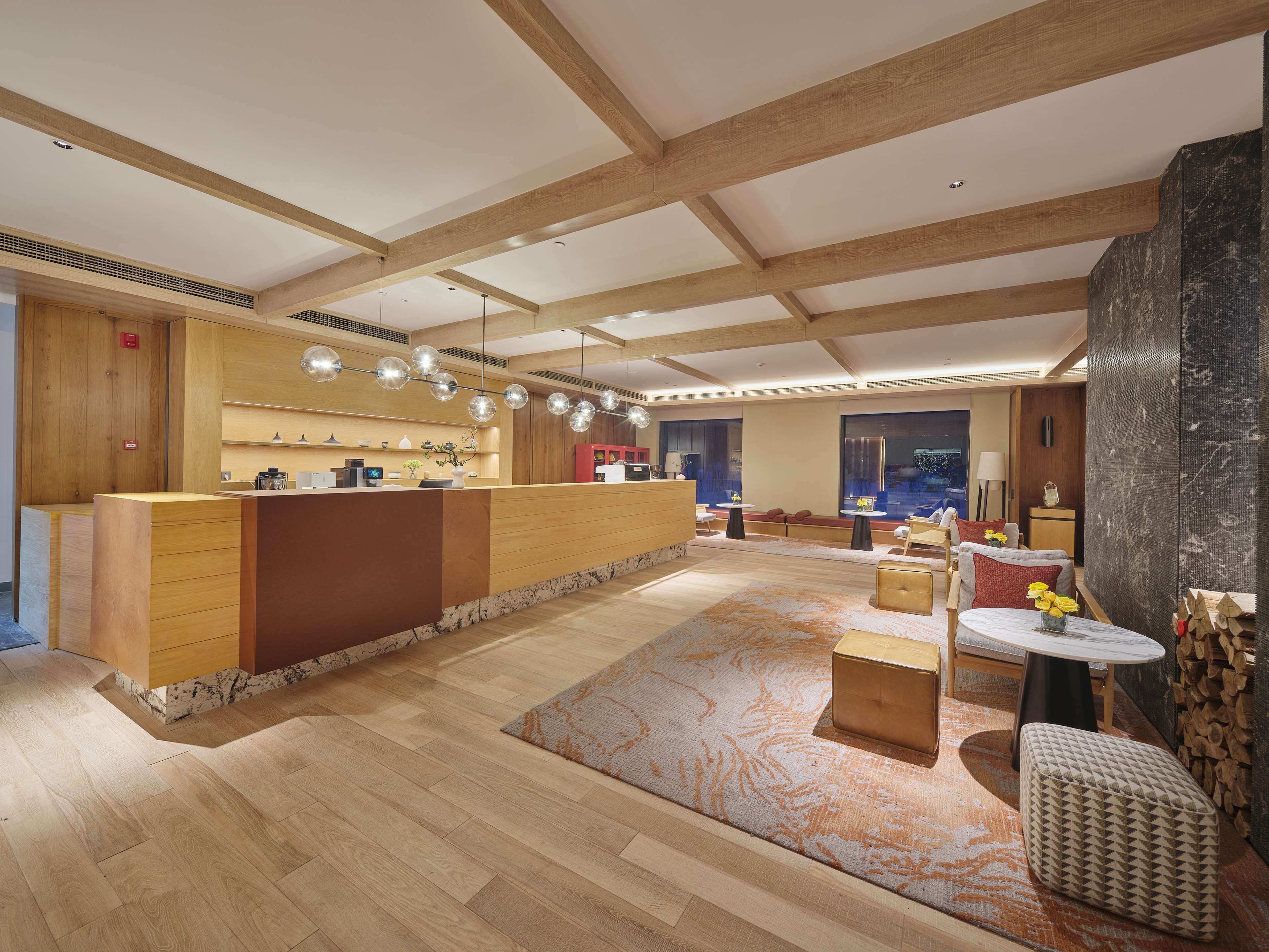 Een moderne hotellobby met een receptiebalie, zithoek en grote ramen.