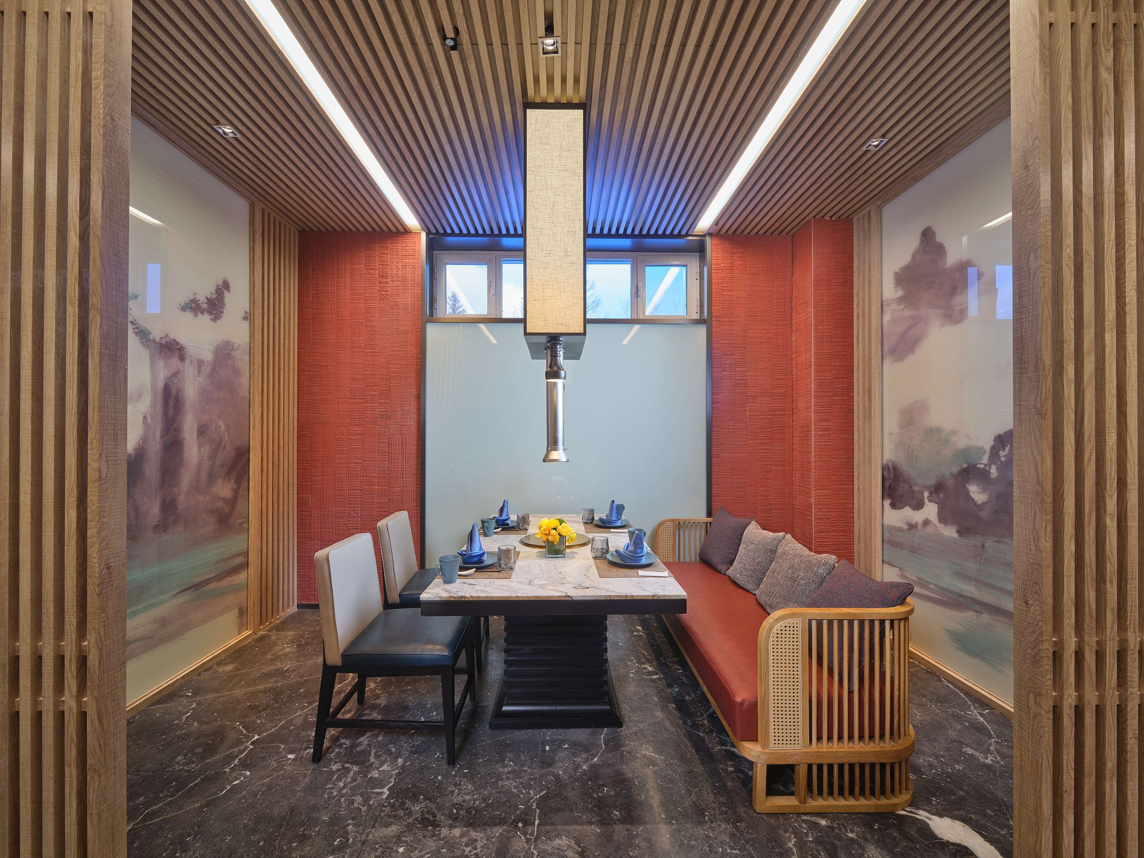 A modern dining area with a long table, chairs, and a cushioned bench.