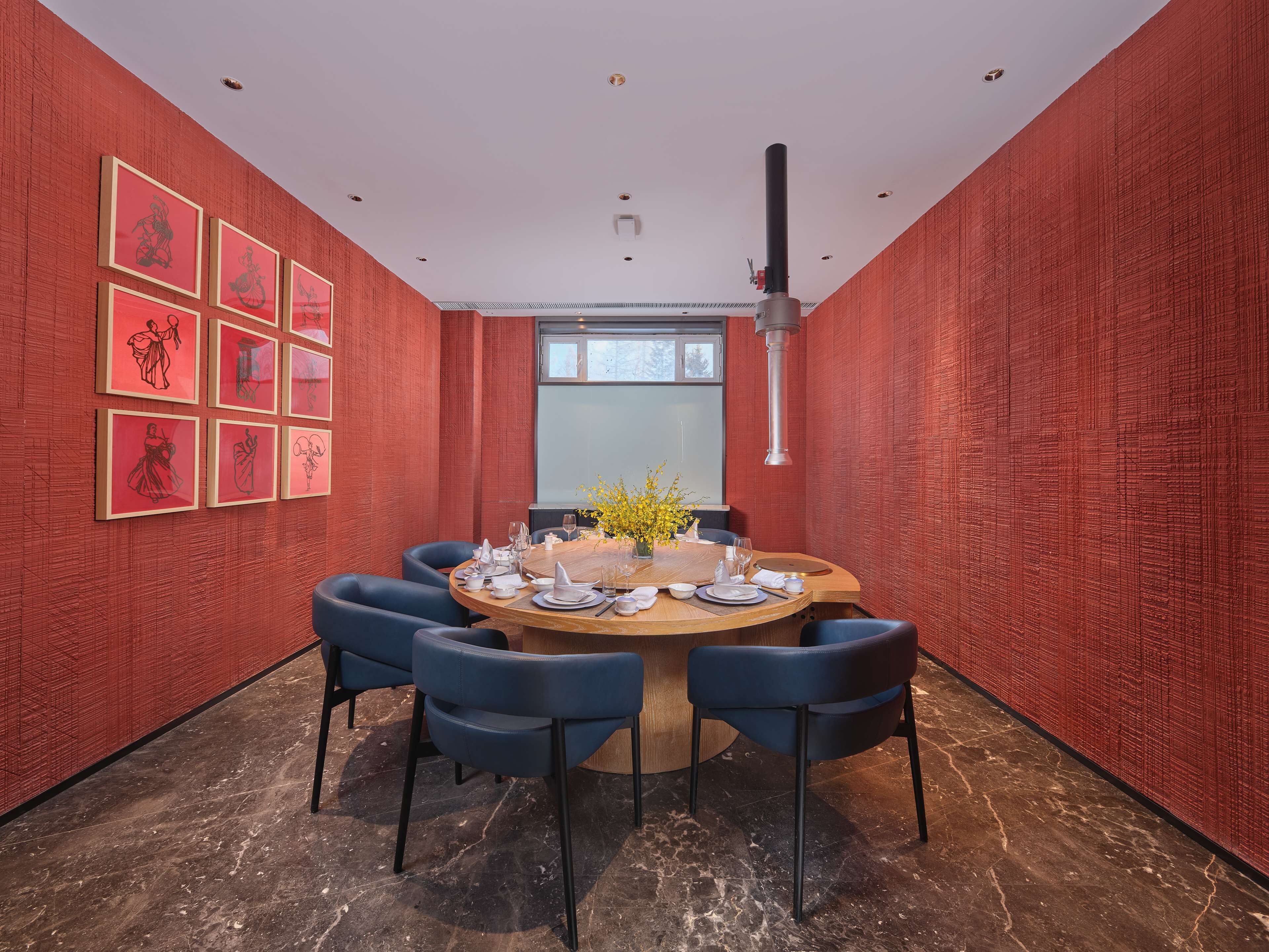 A conference room with a round table, six chairs, and red textured walls.
