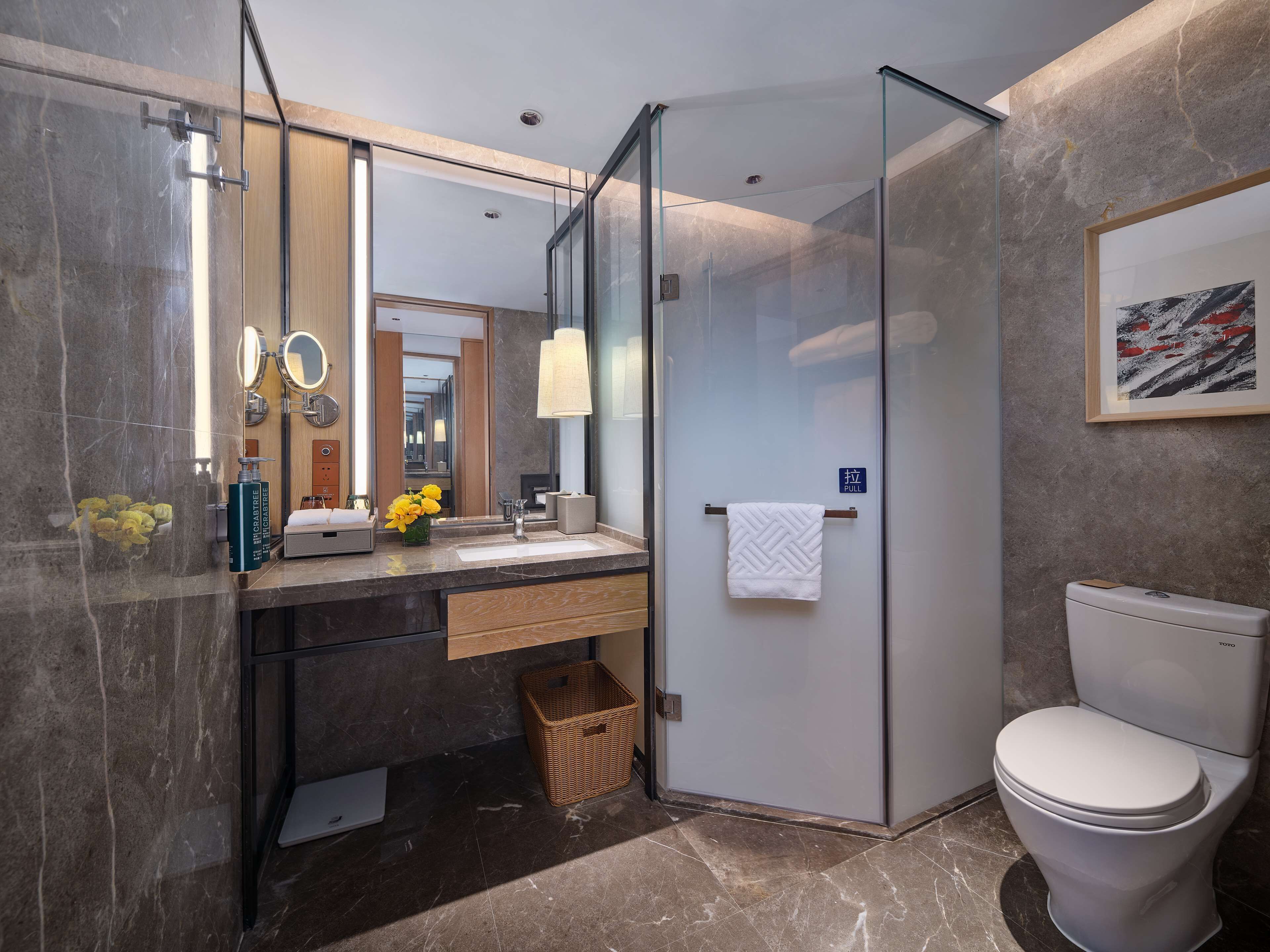 Ein modernes Badezimmer mit Duschkabine aus Glas, Marmorwaschbecken und weißer Toilette.