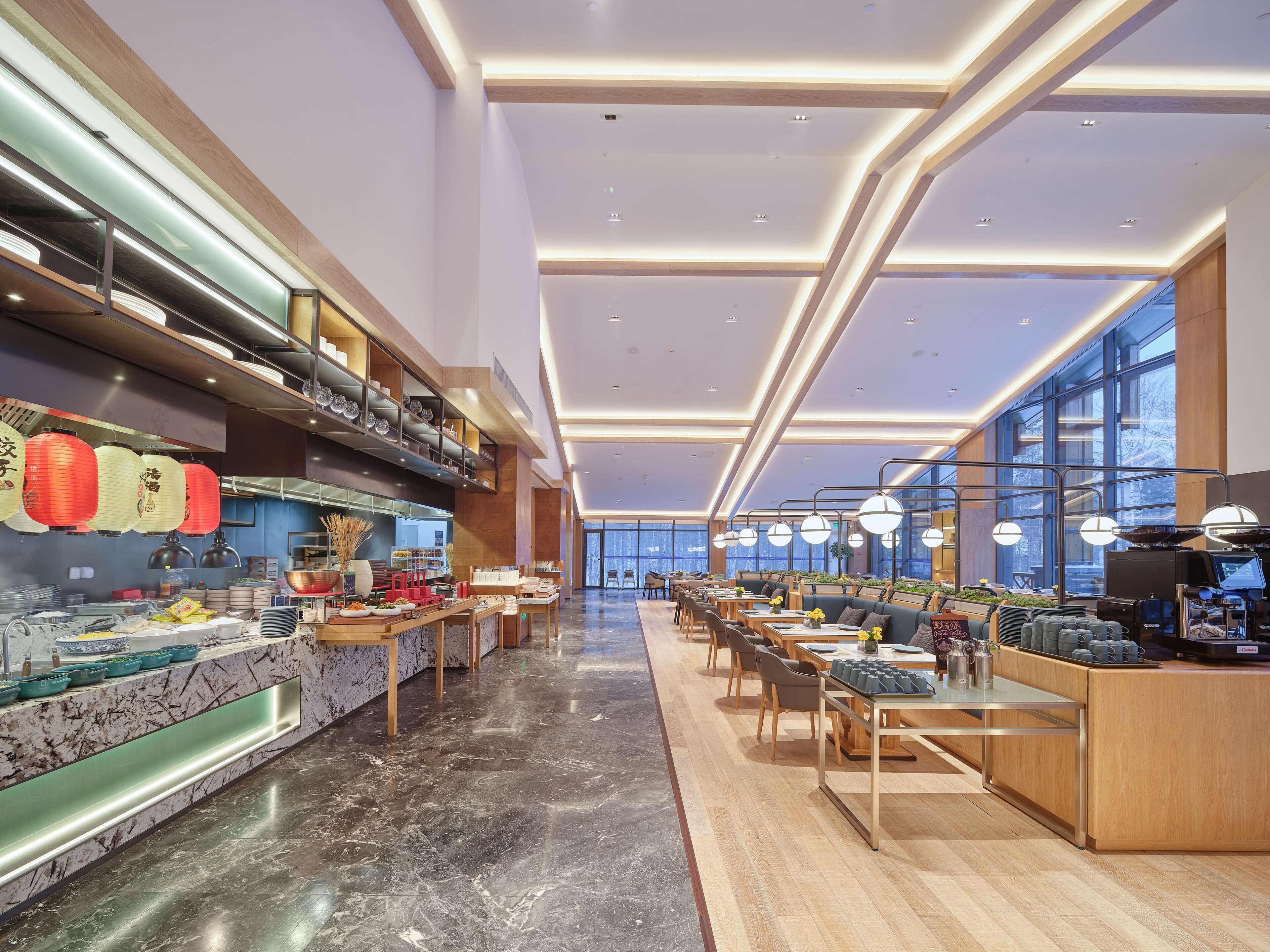 Un interior de restaurante moderno con una barra larga, zona de estar y ventanas amplias.