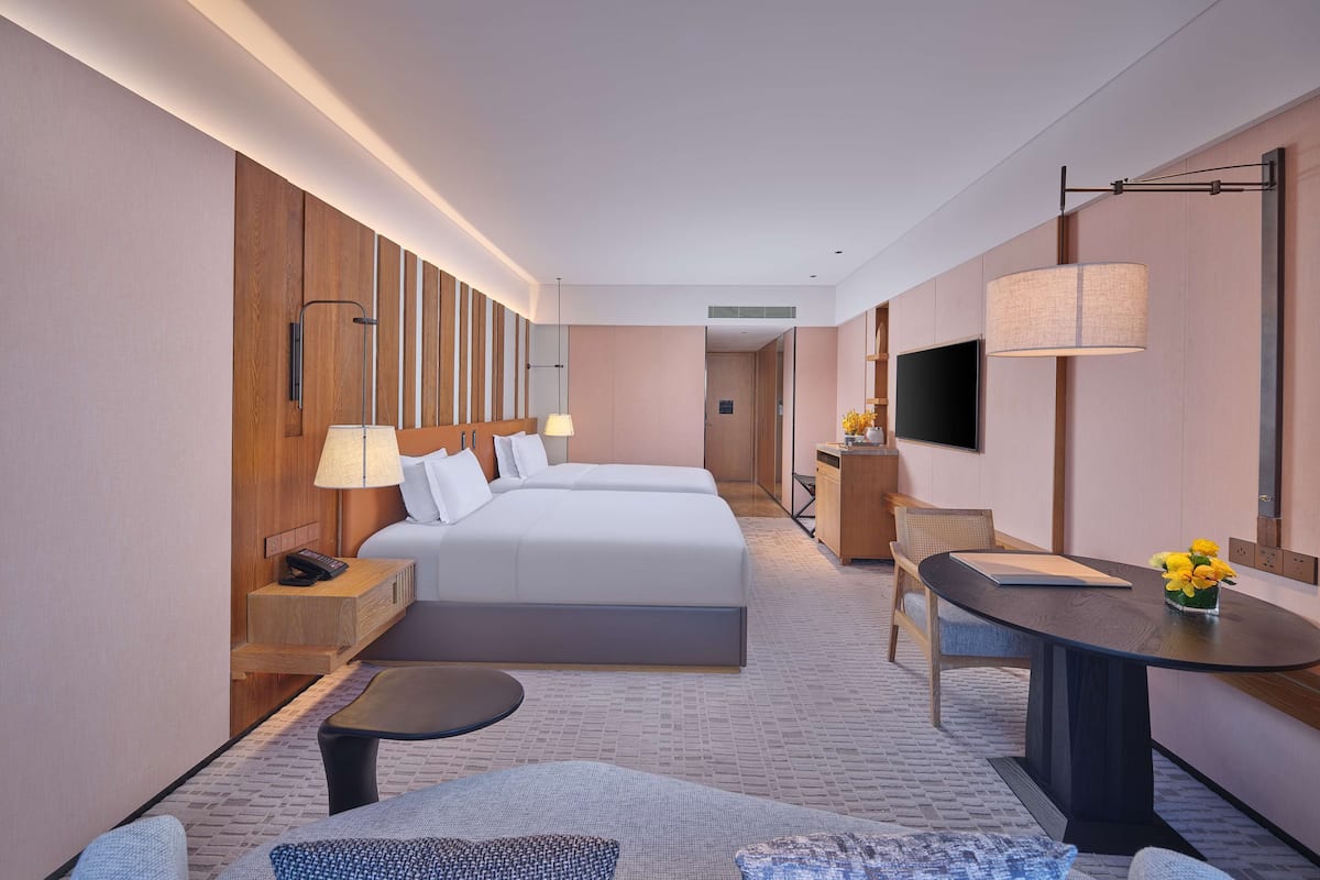 A hotel room with a large bed, a desk, a chair, a sofa, and a TV.