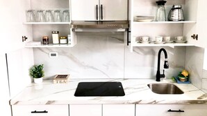 Une cuisine avec des armoires blanches, un robinet noir et un plan de travail en marbre.
