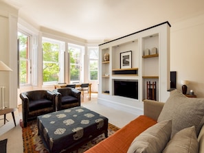 Una sala de estar con chimenea, dos sillones, un sofá y una mesa de centro.