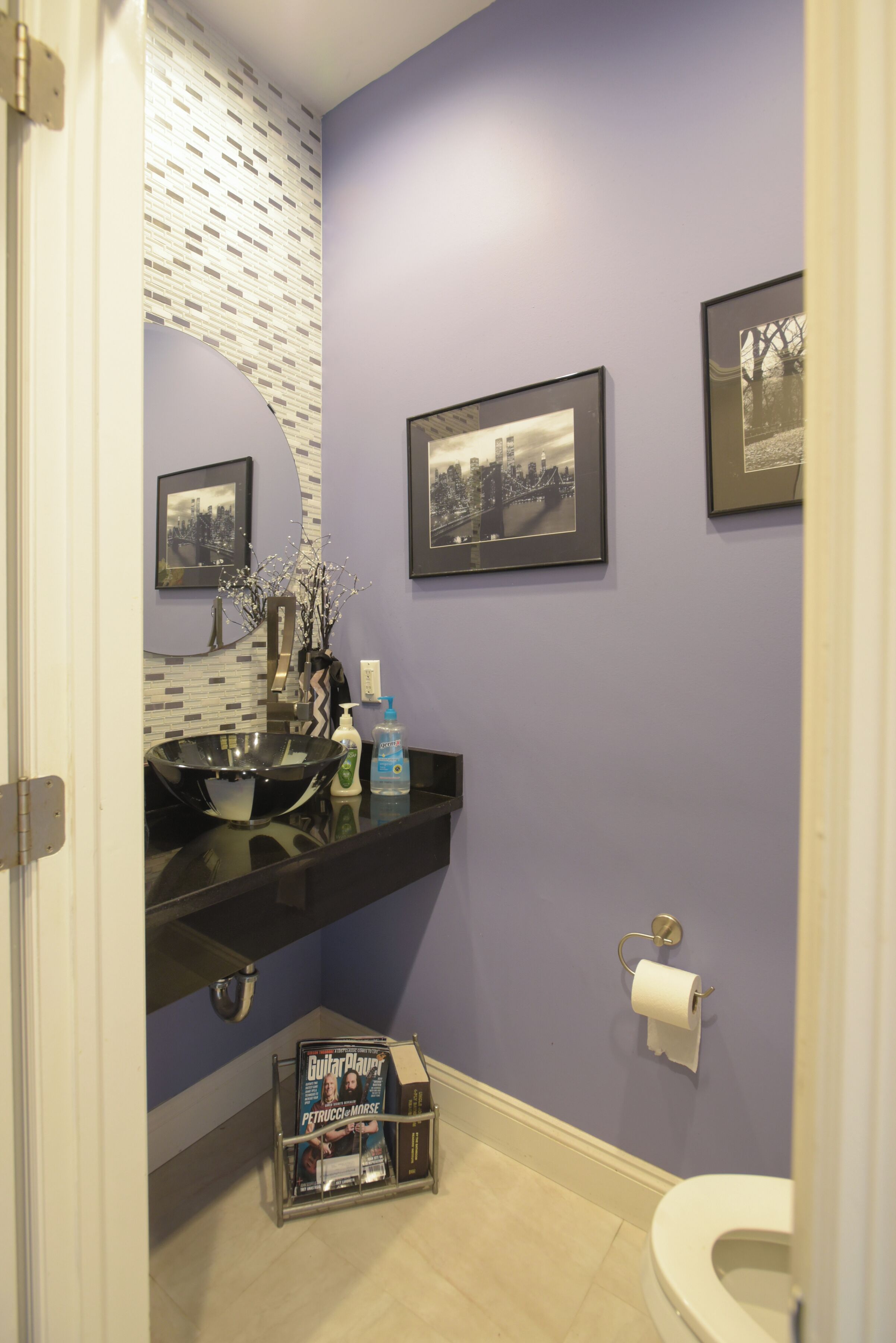 A bathroom with a black vanity, a toilet, and framed pictures on the wall.