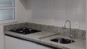 Una cocina con armarios blancos, encimera de granito, pileta doble y estufa a gas.