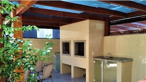 Un área de cocina al aire libre con salpicadero de azulejos, una encimera y una silla.